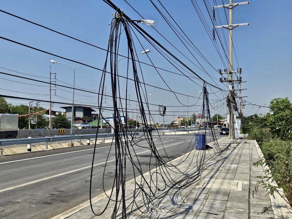 เตือนภัย!! สายไฟฟ้า-สายสื่อสารห้อยระโยงระยางบนทางเดินเท้า หวั่นช็อตคนตาย