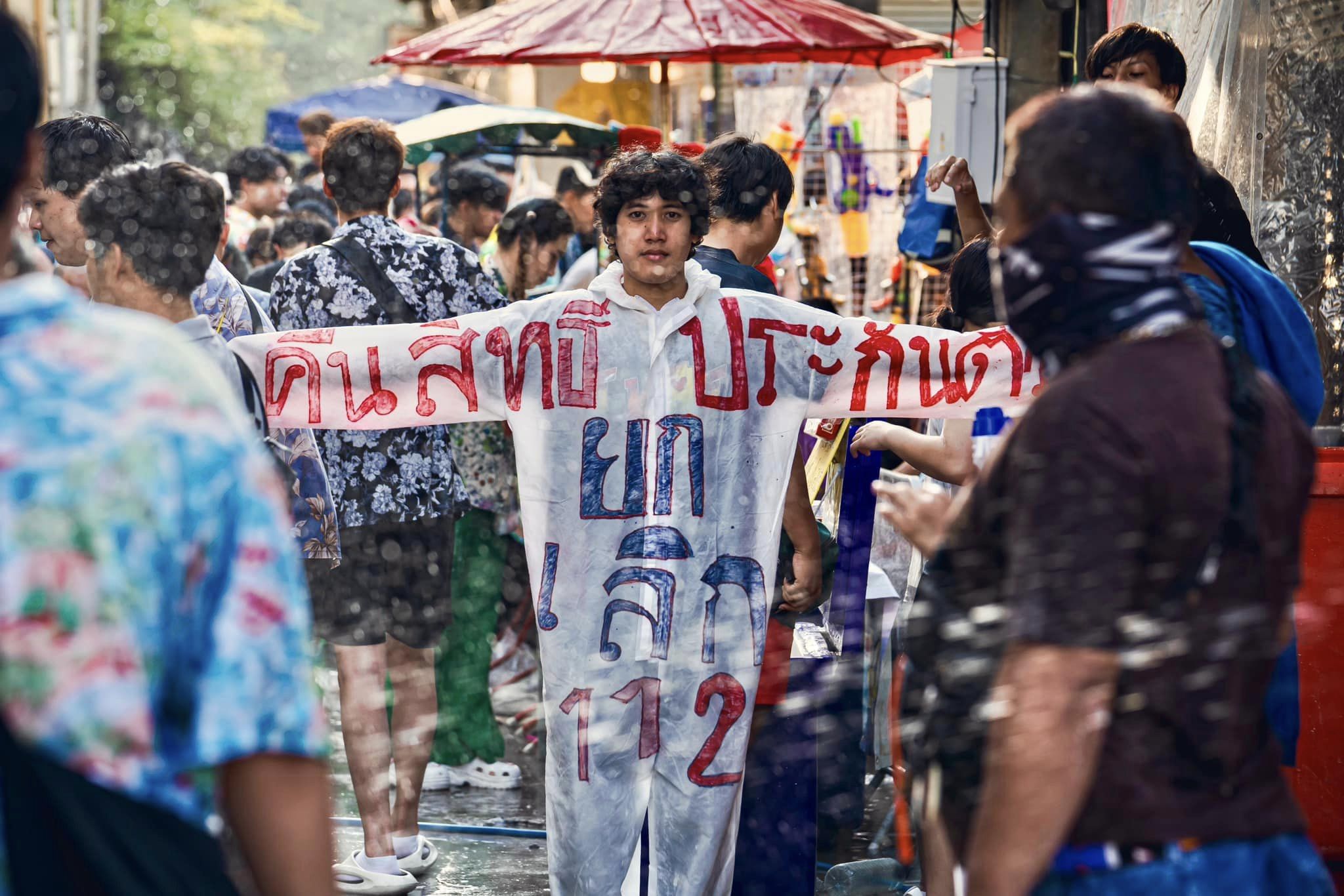 "ต๊ะ คทาธร" โผล่ถนนข้าวสาร ใส่ชุด PPE เขียนข้อความ "คืนสิทธิการประกันตัว ยกเลิก 112"