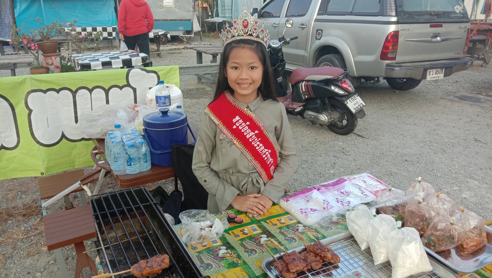 หนูน้อยวัย 10 ขวบ ไอเดียบรรเจิดสวมมงกุฎพร้อมสายสะพายช่วยแม่เรียกลูกค้าซื้อหมูปิ้ง